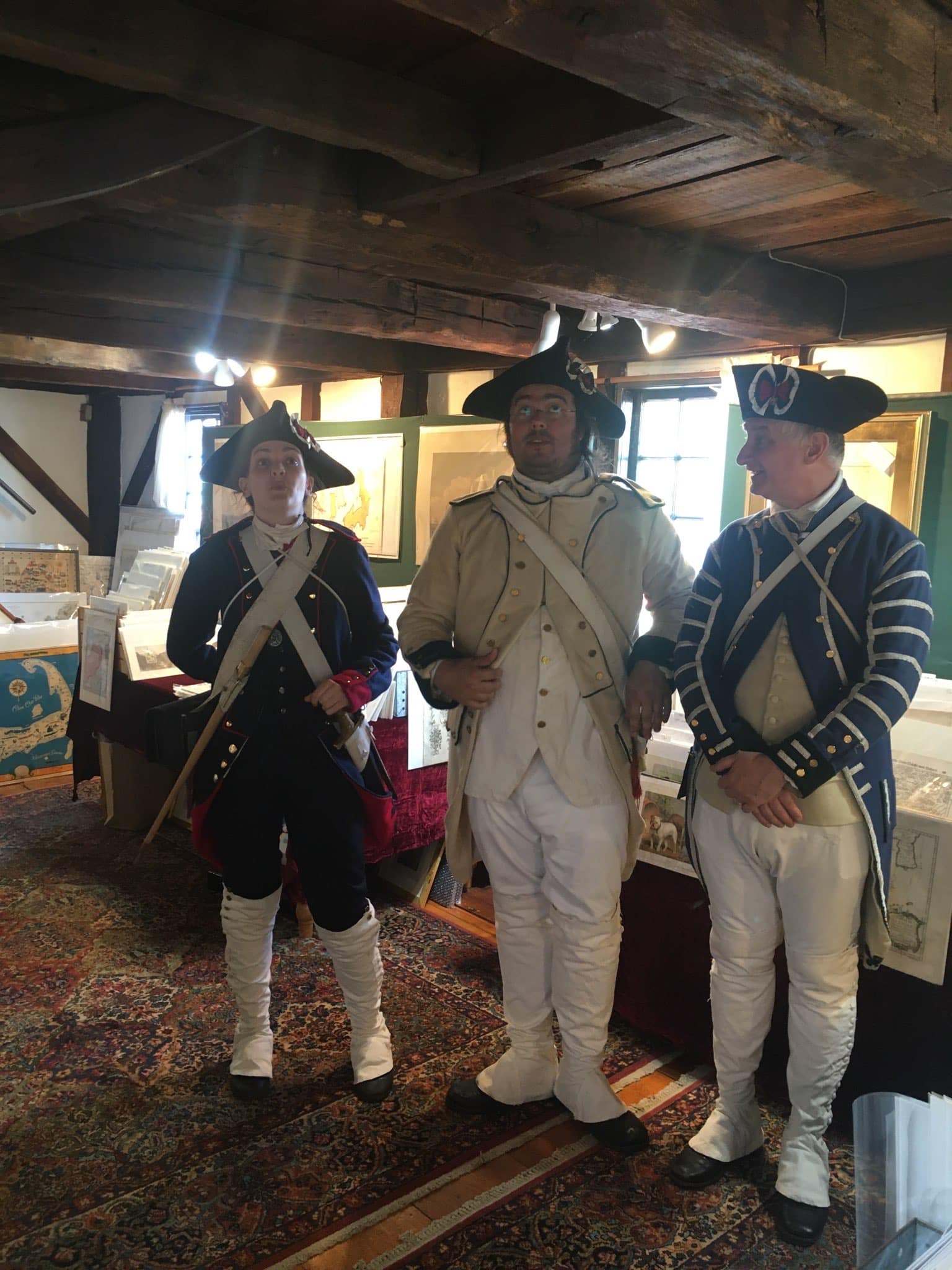 Three Revolutionary War reinactors in French military uniforms, the uniforms are extremely detailed,. They are inn Newport RI, on historic Bowens Wharf. Inside an unusual shop, or Antique Prints and Old Maps Gallery. Their expressions show awe in the 18th Century freight elevator, smack dab in the middle of, Anne Hall Antique Prints Gallery.