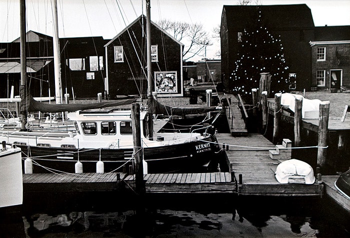 Scene shows the Kermit, a boat docked at Bowen's Wharf, years ago. The building behind the Christmas tree, happens to be one of the oldest on Bowen's Wharf. In fact, it dates to early Colonial America. It is located at 12 Bowen's Wharf Newport RI, 02840. Built c.1760 it was the Wharf warehouse, however today it is the: Anne Hall Antique Prints Gallery.